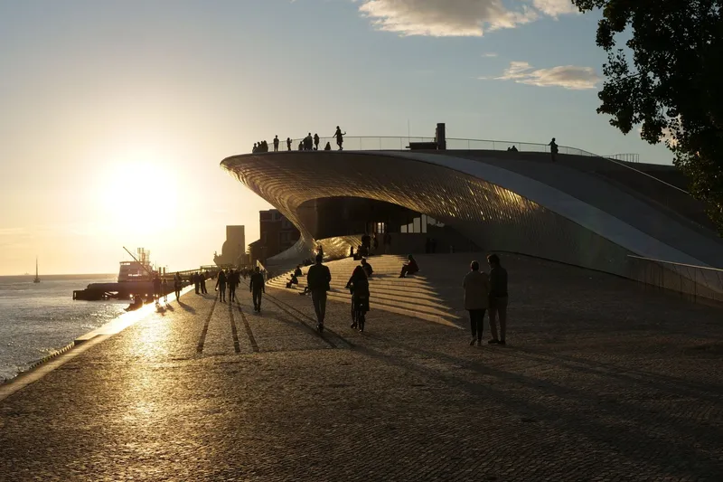 Undulating rooftop terrace of MAAT Lisbon with visitors at sunset